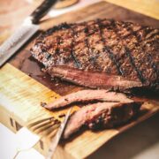A flank steak with a long steak knife and grill marks.