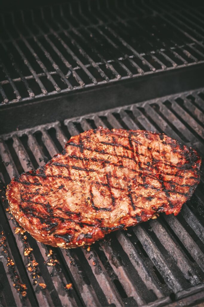 The steak on the grill, flipped with grill marks.