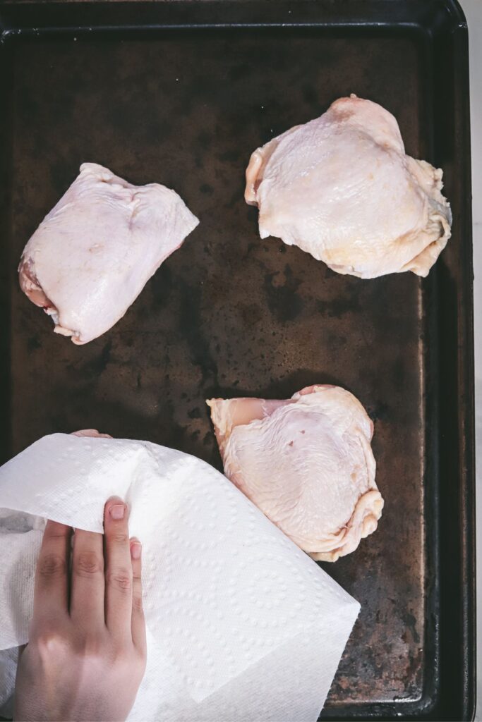 Patting chicken thighs dry with paper towel. 