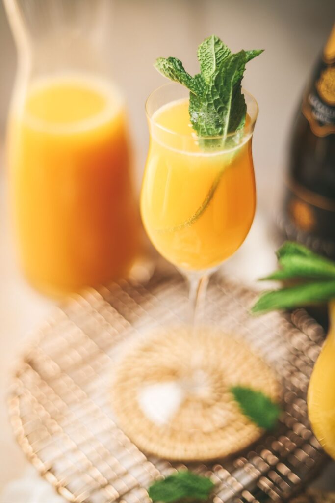 A mimosa mocktail with orange juice in the background. 