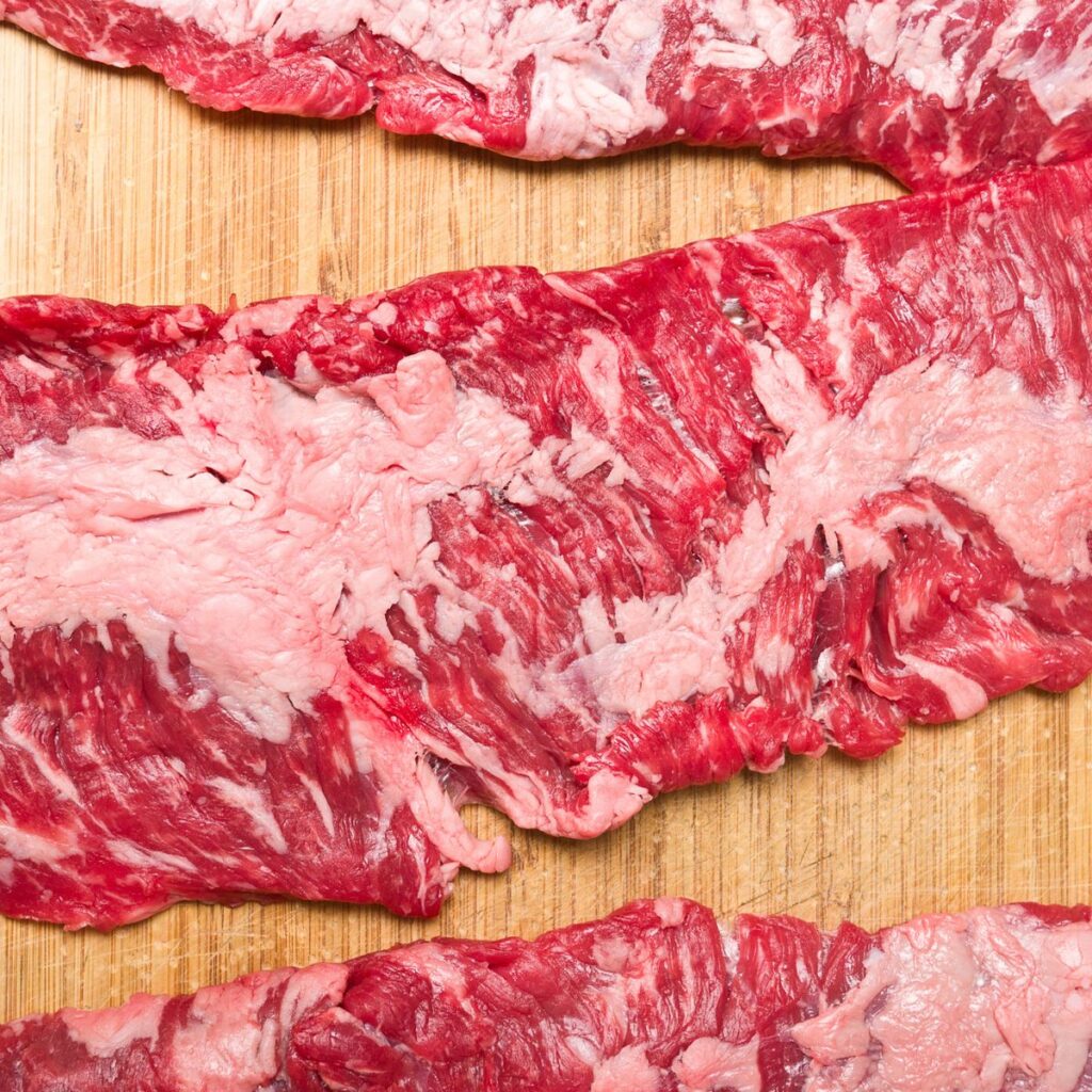 A photo of several raw skirt steaks. 