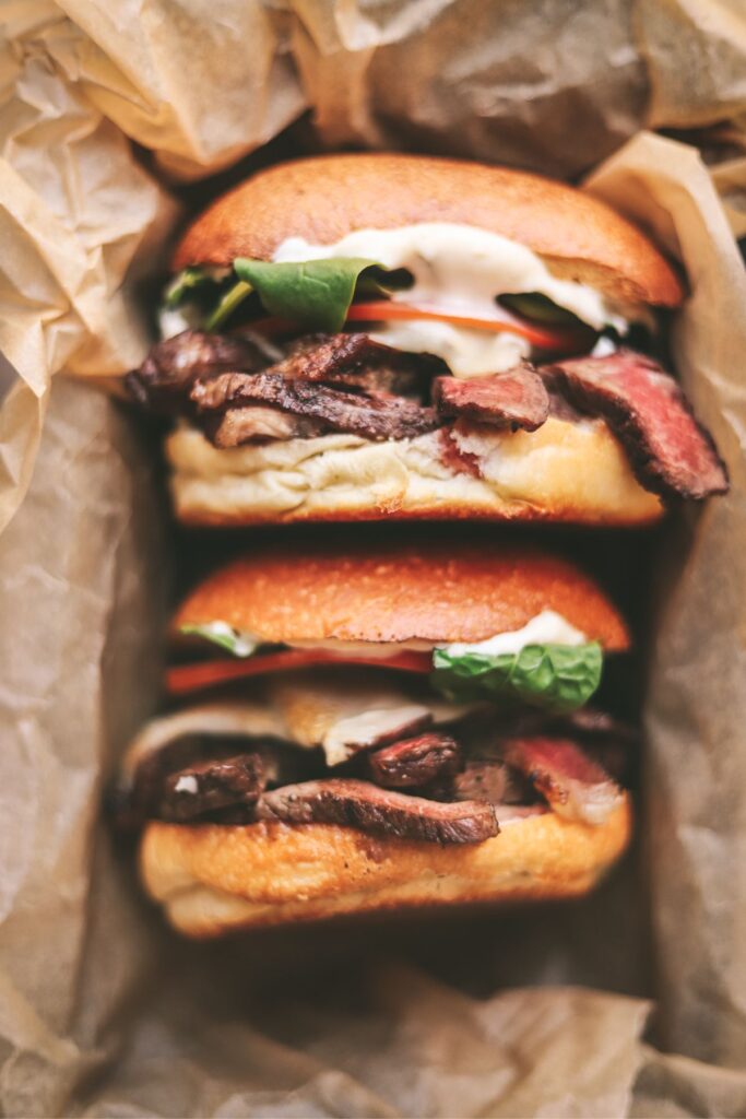 Two steak sandwiches stacked on top of each other in parchment paper. 