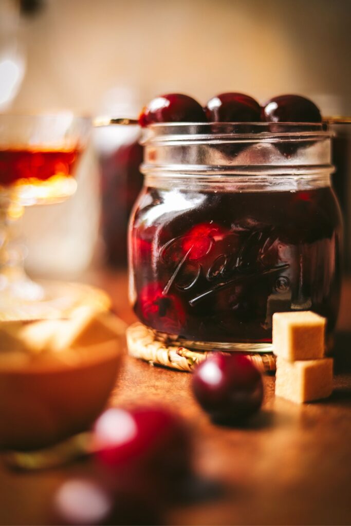 A jar of bourbon soaked cherries, brown sugar, and fresh cherries. 