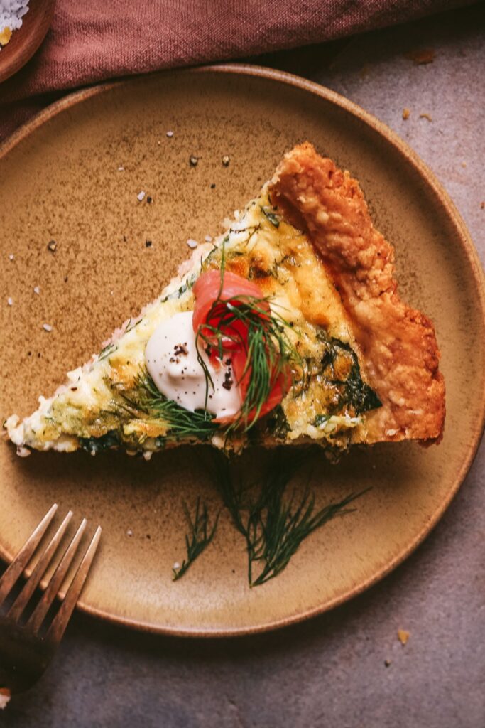 Salmon and spinache quiche with a gold fork. 