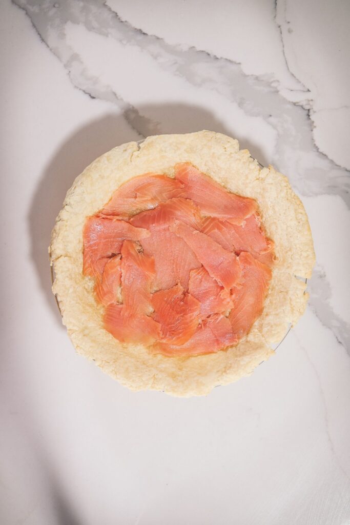Crust with smoked salmon layered on the bottom. 