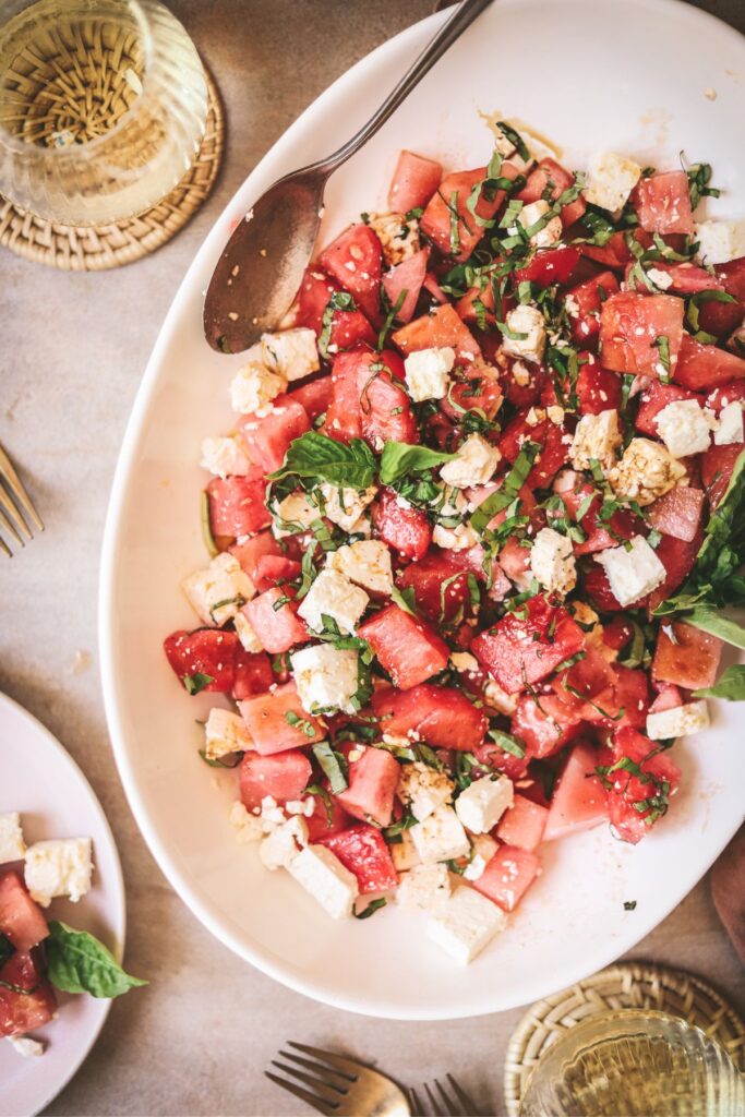 Watermelon basil salad with white wine and a serving spoon. 