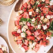Watermelon feta salad with basil on a white platter.