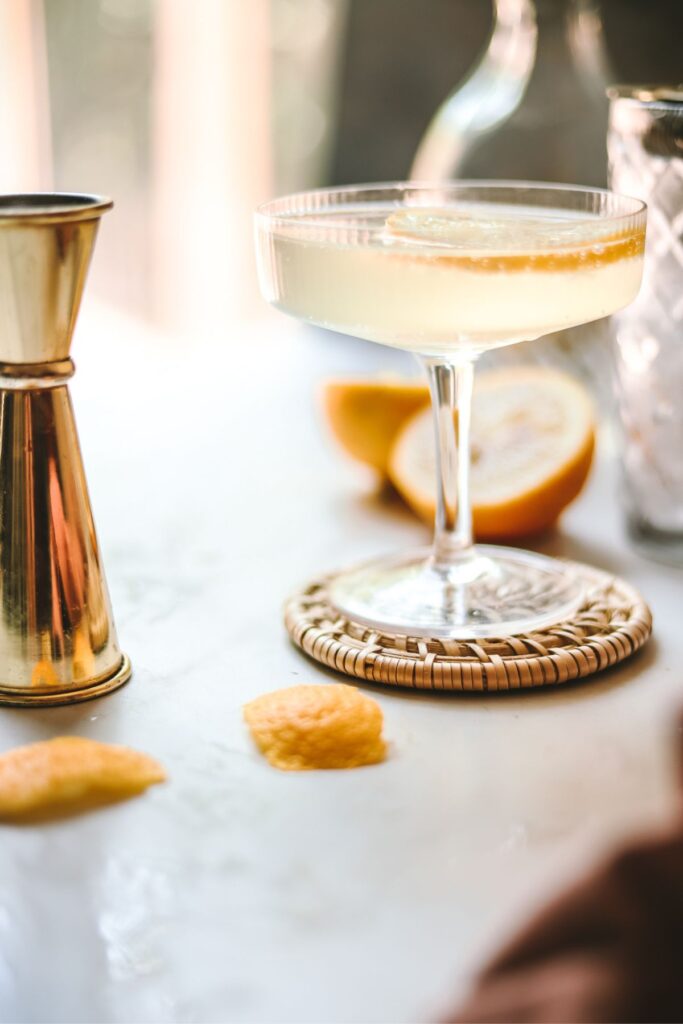 A French 76 drink with barware and lemon surrounding. 