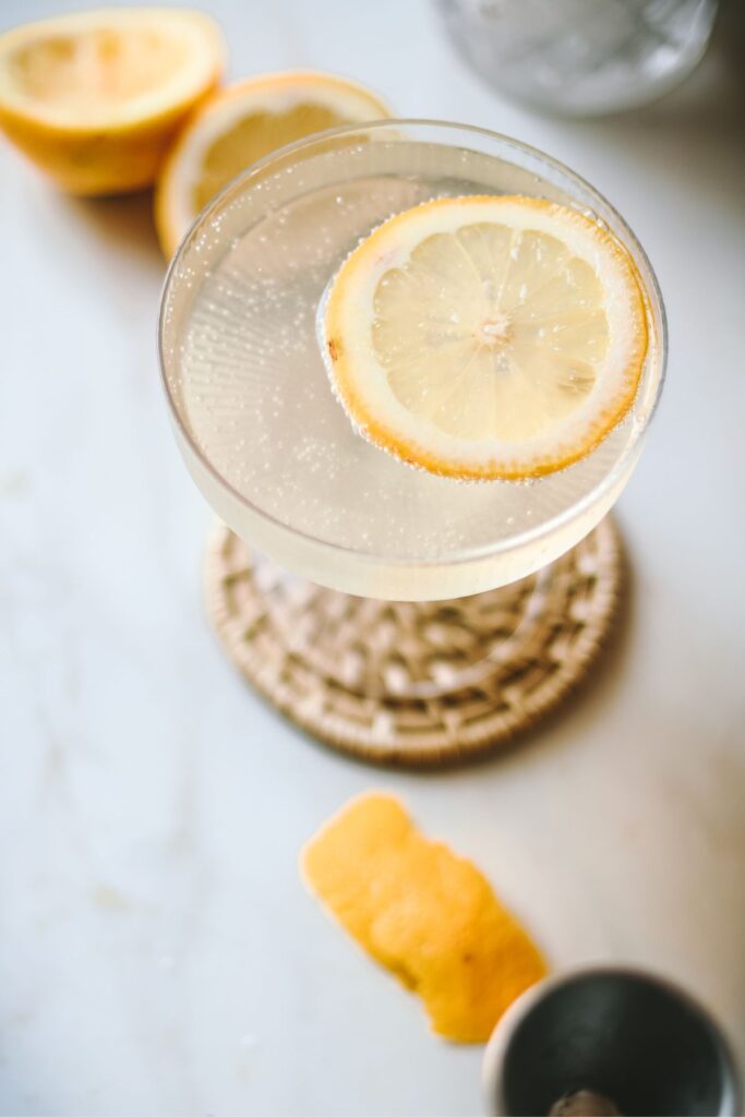 A french 76 cocktail with a sliced of lemon. 