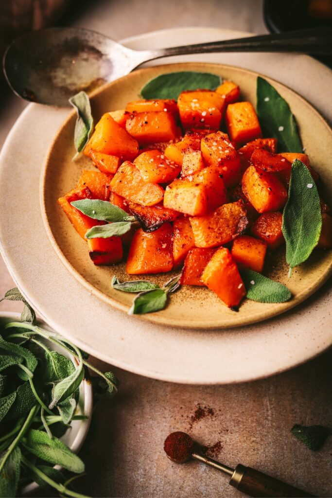 A plate of roasted butternut squash with sage leaves. 