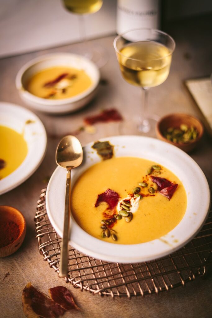 A bowl of roasted butternut squash soup with pumpkin seeds and prosciutto.