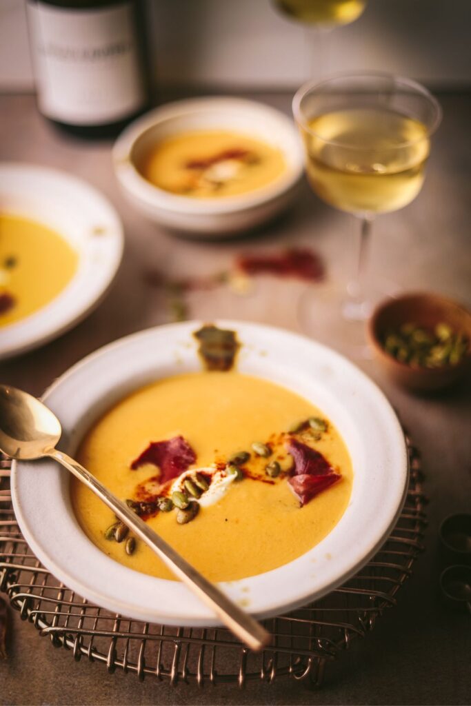 A bowl of butternut squash soup, with prosciutto. 