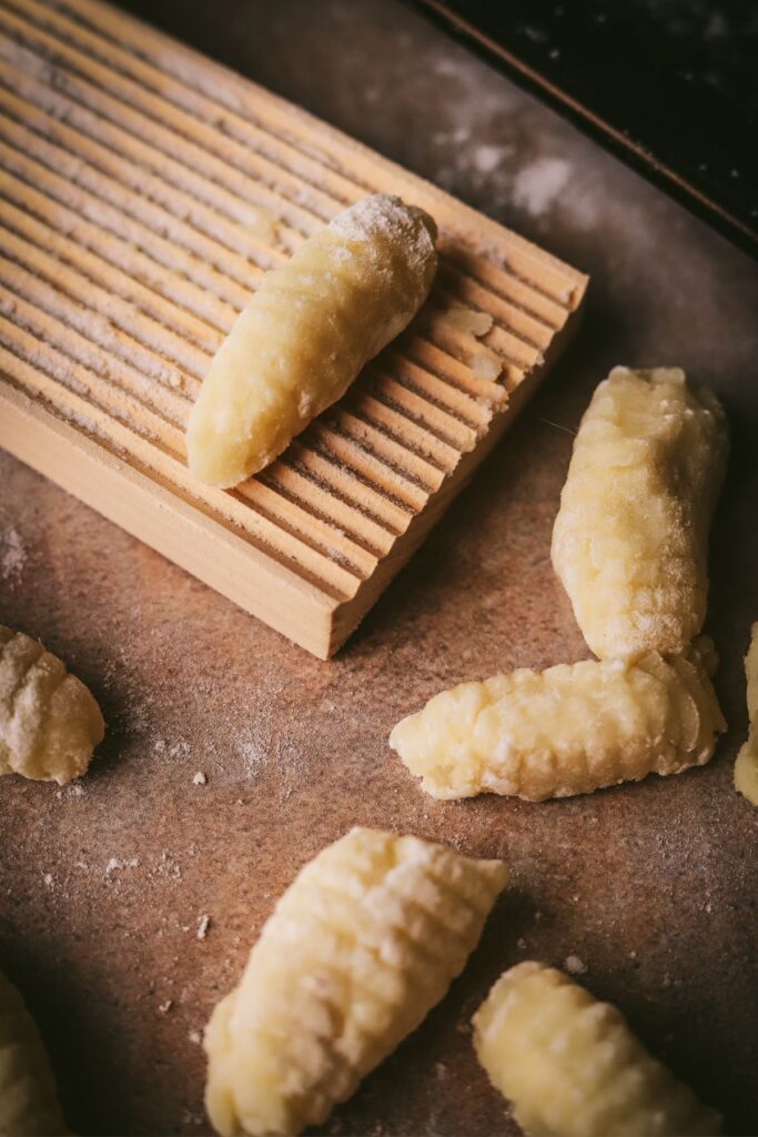 Homemade gnocchi being rolled on a gnocchi board with flour. 