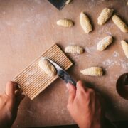 Gnocchi being hand rolled with flour on a board.