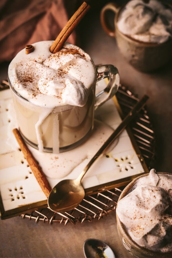 A maple latte with cinnamon whipped cream dripping down the sides of the mug. 