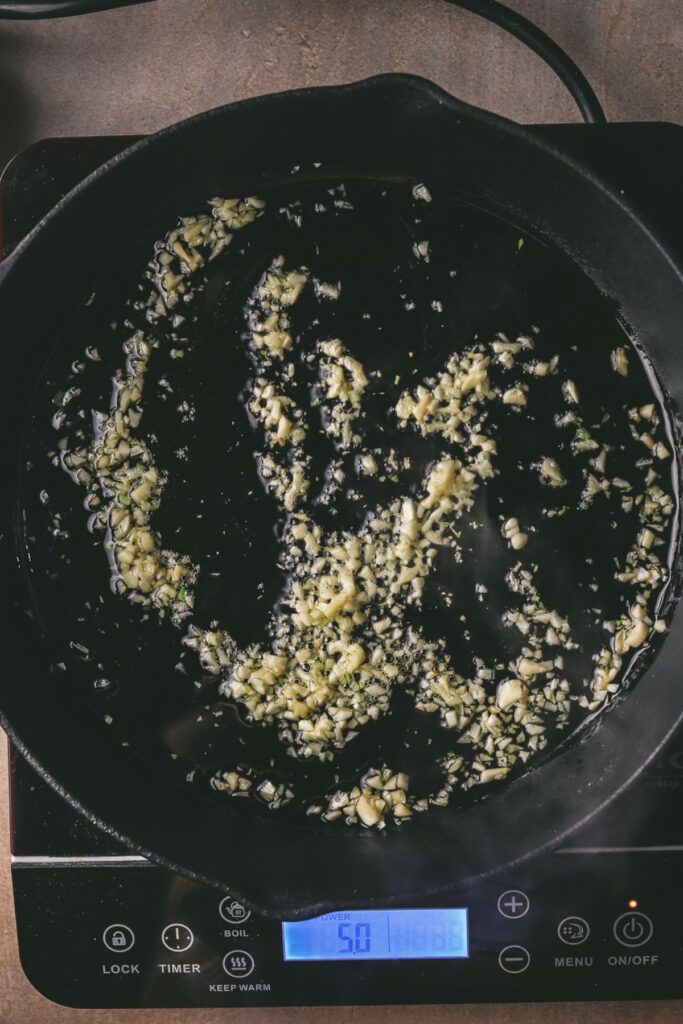 Garlic sautéing in olive oil in a pan. 