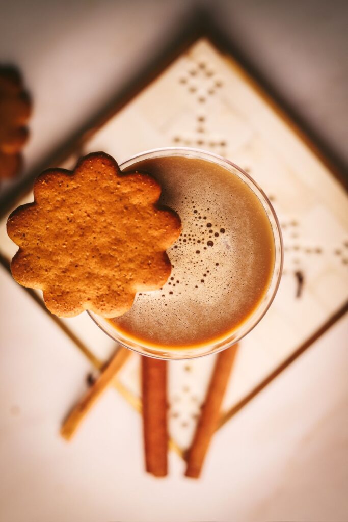 An overhead look at a gingerbread martini garnished with a cookie and cinnamon sticks.
