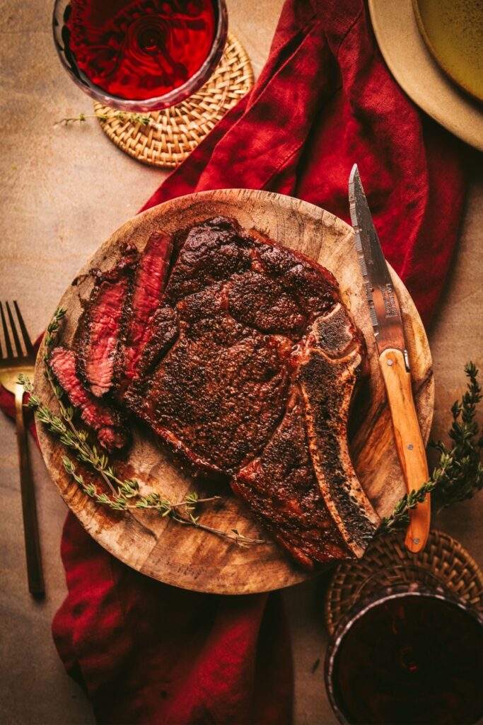  A reverse-seared ribeye steak with steak knives, red wine, and herbs. 