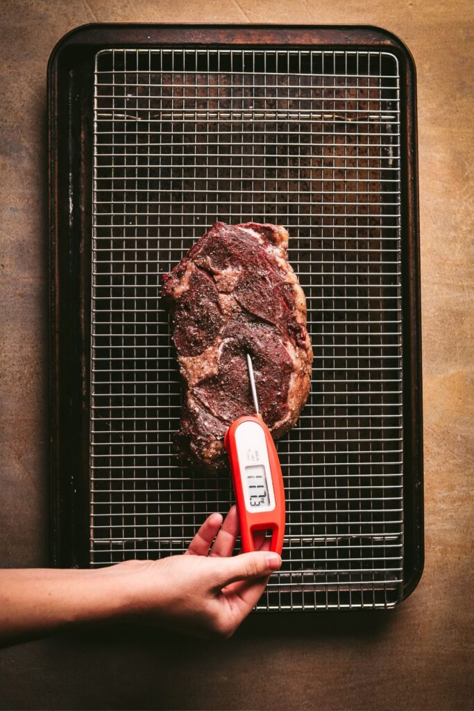 Checking the internal temperature of the steak with a meat thermometer. 