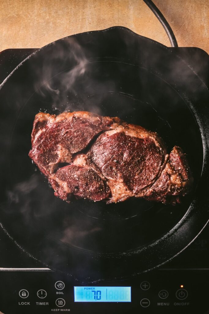 Searing the ribeye in a cast iron skillet, with smoke. 