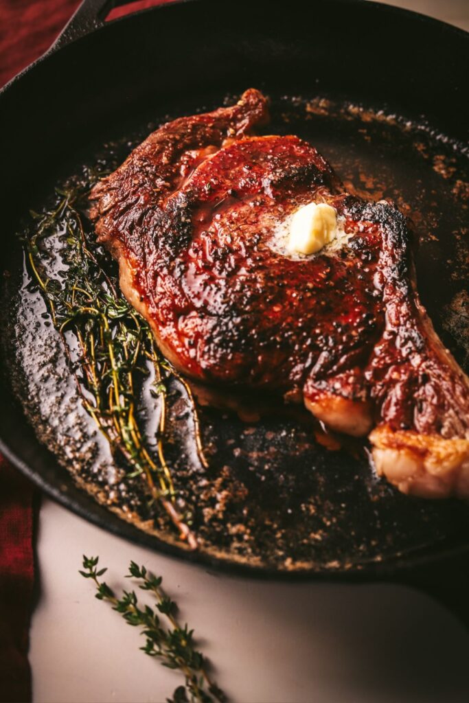 A seared bone in ribeye steak in an oven safe pan. 