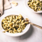 A bowl of pasta covered in creamy pesto sauce.