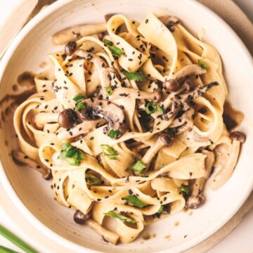 A bowl of miso mushroom pasta with green onion and sesame seeds.