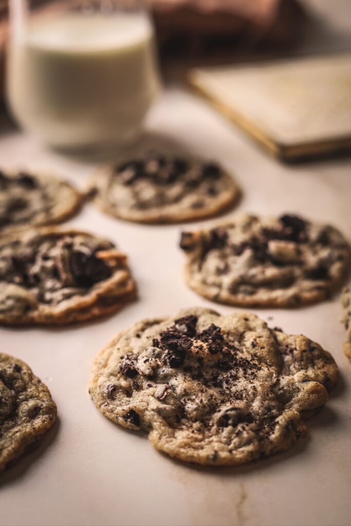 Several oreo chocolate chip cookies with a glass of milk. 