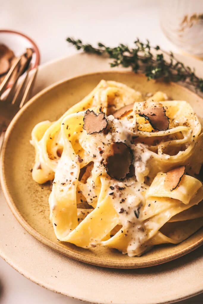 A plate of truffled pasta with thyme and cream sauce. 