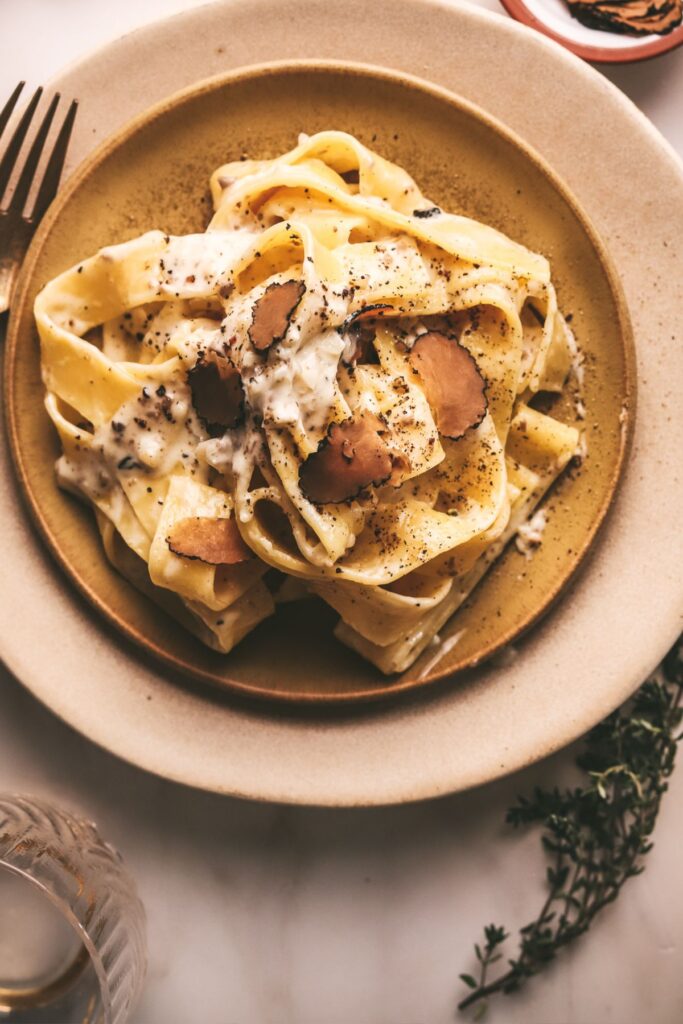 A plate of truffle pasta with pappardelle noodles and thyme. 
