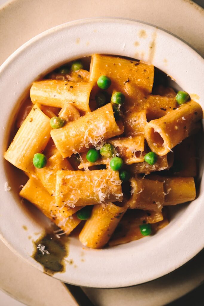 A bowl of pasta with pancetta and peas. 