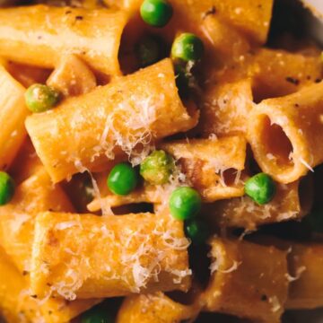 A close up of rigatoni with pancetta, peas and parmesan.