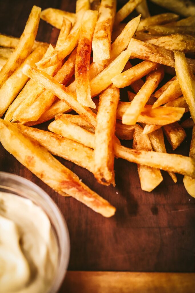 Crispy homemade french fries on a wooden serving board. 