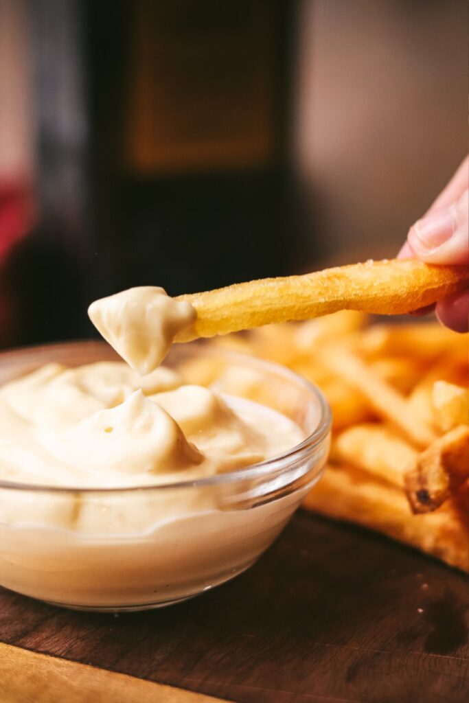 Dipping French fries in an aioli. 