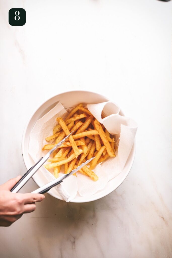 Fries in a paper towel lined bowl, and seasoning.