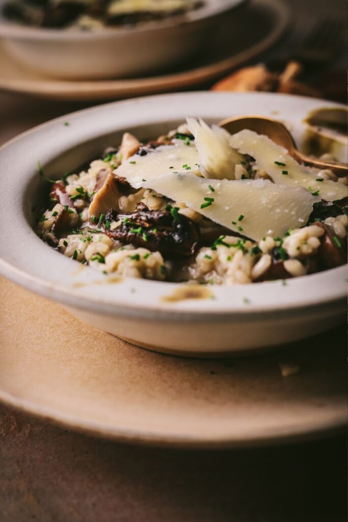 A bowl of cozy mushroom risotto, with parmesan cheese and chives. 