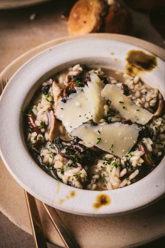 A creamy bowl of mushroom risotto garnished with parmesan and chives. 