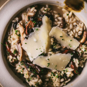 A bowl of mushroom risotto with parmesan shavings on top.