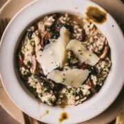 A bowl of mushrooms risotto with truffle oil, chives, and parmesan cheese.