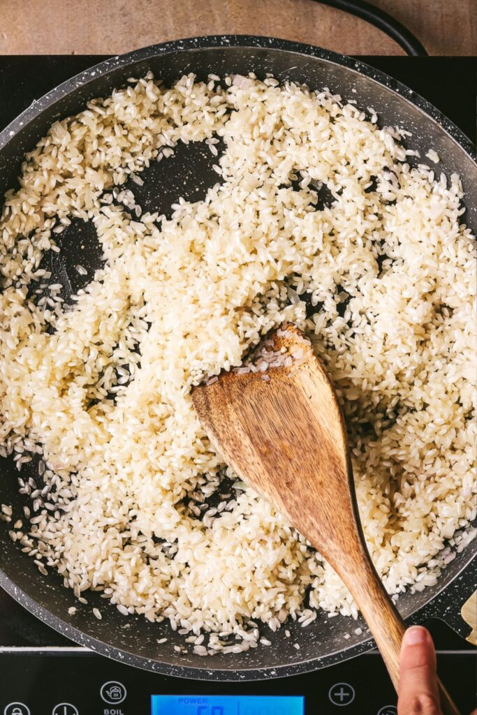 Adding the rice to the pan with the shallots.