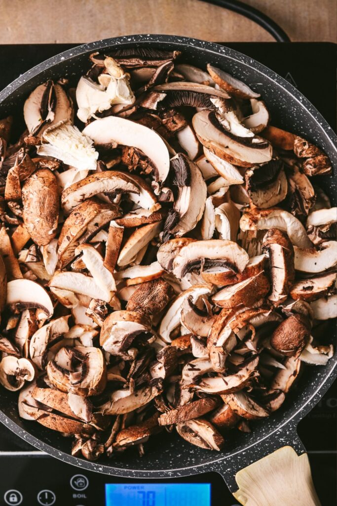 Adding the mixed mushrooms to a pan with olive oild. 