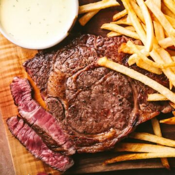 A platter of steak frites, with ribeye steak, French fries, and Béarnaise sauce.