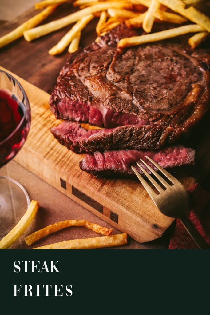 Steak frites (steak and french fries, with gold fork and red wine on a cutting board. Title text.