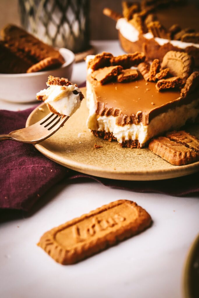 A slice of Biscoff cheesecake, with the Lotus Biscoff cookies and a purple napkin.