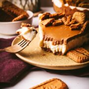 A piece of Biscoff cheesecake with several bites out of it, one of the bites on a fork.