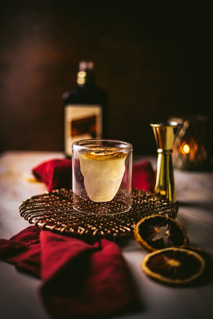 Corpse reviver no. 2 cocktail with triple sec in the background, napkin and dried citrus. 