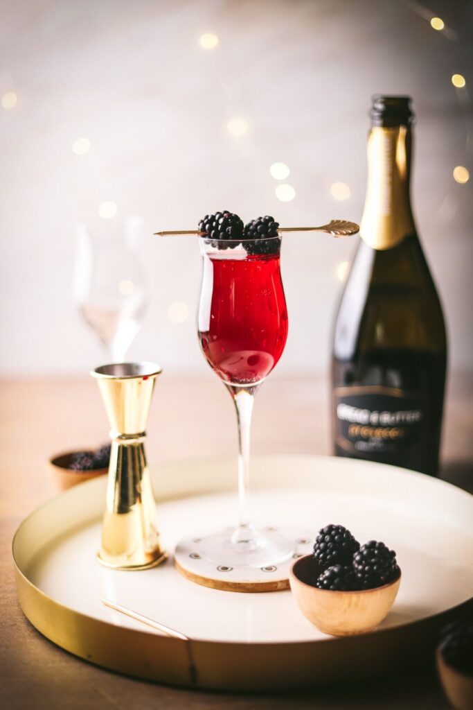 A Kir Royale cocktail, garnished with blackberries.