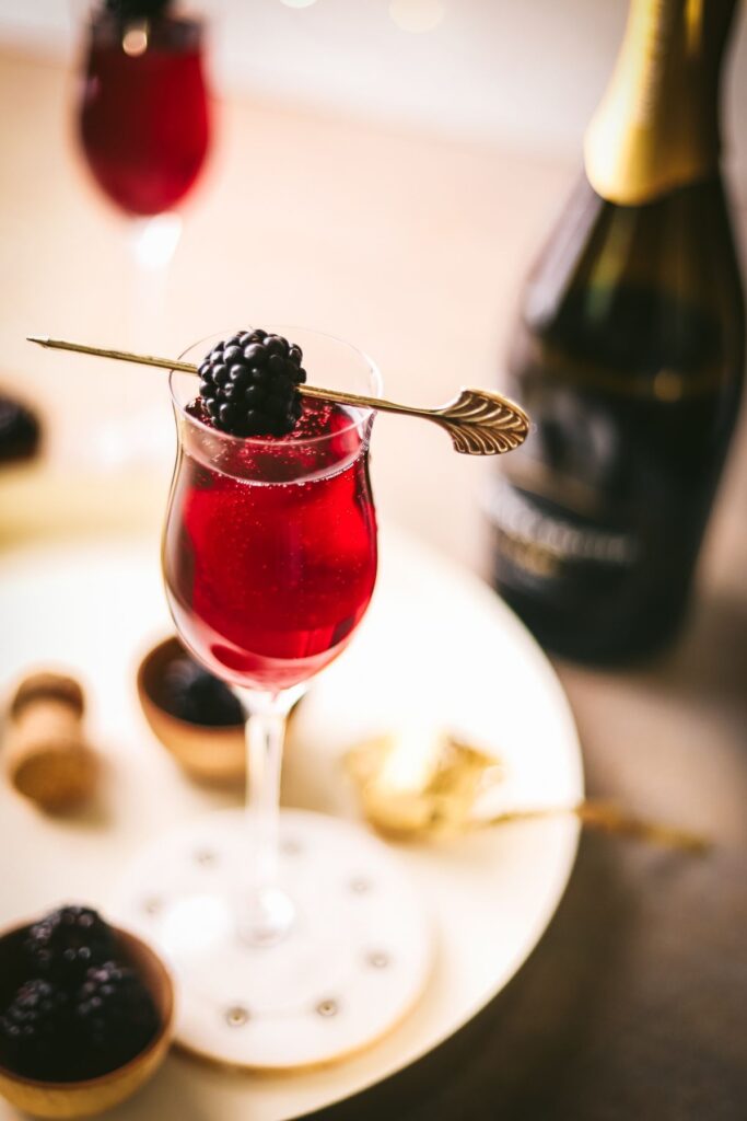 Two Kir Royale cocktails, with sparkling wine and blackberries.