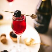 A Kir Royale cocktail with Prosecco cork and blackberries.