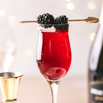 A Kir Royale cocktail with Prosecco in the background.